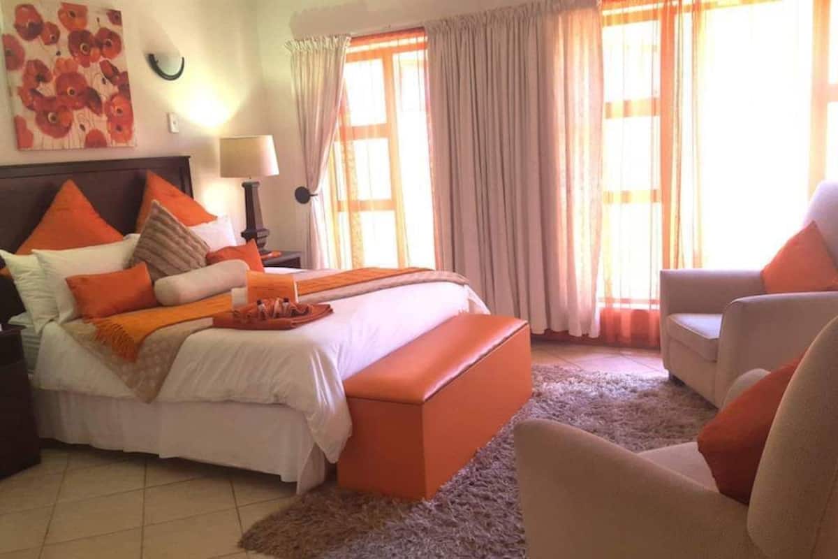 Habitación de hotel con una cama, una silla, una lámpara y un cuadro en la pared.