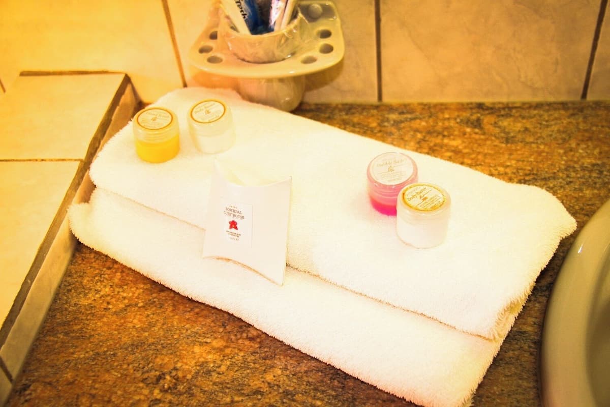 Un baño con una toalla blanca sobre una encimera de granito, tres pequeños frascos de artículos de tocador y una caja de pañuelos.