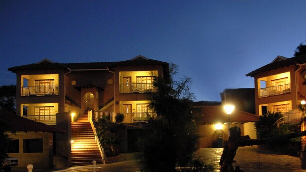 Un edificio residencial de varios pisos con una escalera central, varios balcones y una entrada bien iluminada.
