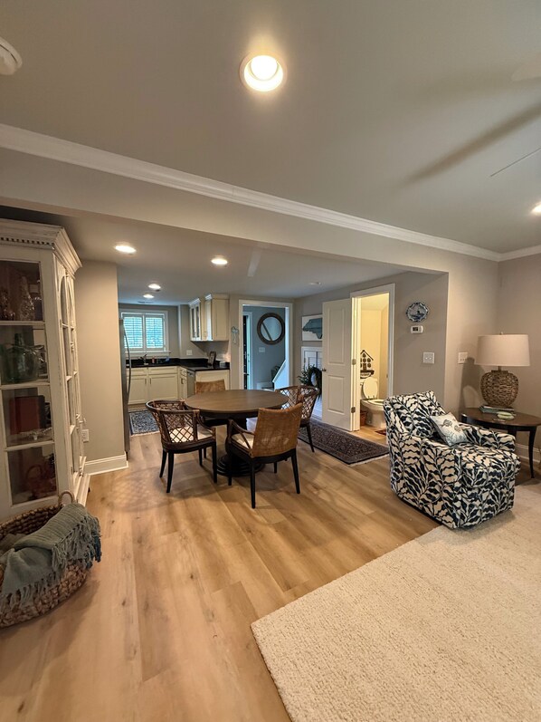 Un salón amplio con una mesa de comedor, sillas, un sillón estampado y una cocina al fondo.