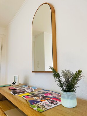 Ein Holztisch mit Zeitschriften, einer Topfpflanze und einem an der Wand befestigten Spiegel.