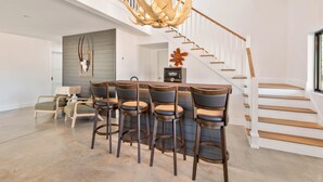 A modern kitchen with a bar area, wooden staircase, and a unique antler chandelier. - 3-bedroom barn in gorgeous Folkston with AC for relaxing stays (Folkston)