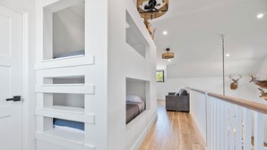 A modern interior with a staircase, built-in shelving, a grey sofa, and a ceiling fan. - 3-bedroom barn in gorgeous Folkston with AC for relaxing stays (Folkston)