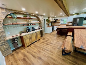 A kitchen with wooden cabinets, a stone arch, and a bar area with stools.