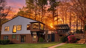 A two-story house with a large deck, a covered outdoor area, and a view of the sunset. - 8 bdrm covered dock, bar and kitchen on the water! hot tub, firepit, sleeps 26, (Henrico)