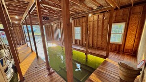 A wooden cabin with a wooden deck, a small pond, and a window with a view. - 8 bdrm covered dock, bar and kitchen on the water! hot tub, firepit, sleeps 26, (Henrico)