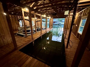 A wooden deck with a pool, wooden beams, and a view of a house.