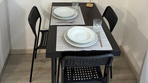 Une table à manger est dressée avec des assiettes, des couverts et des verres, et entourée de chaises noires. Trois panneaux encadrés sont accrochés au mur au-dessus de la table.