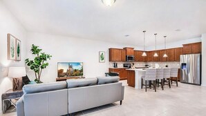 Eine moderne Küche mit Holzausbau, einem Edelstahlkühlschrank und einem Essbereich mit Tisch und Stühlen.