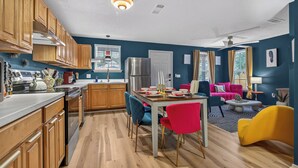 Eine moderne Küche mit Holzschränken, einem Edelstahlkühlschrank und einem Essbereich mit Tisch und Stühlen.