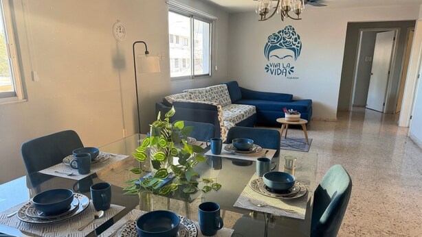 Un coin repas avec une table en verre, dressée pour quatre personnes, entourée de chaises.