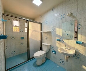 A bathroom with a shower, toilet, sink, and a window.