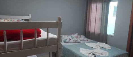 Un dormitorio con una cama individual, una litera, una ventana con cortinas y una mesita de noche.