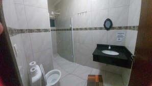 A bathroom with a toilet, a shower, and a sink. - Pousada Ilha do Itacolomi (Penha)