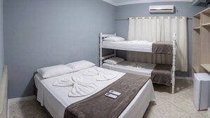 A room with two beds, a small bedside table with a remote control, a wall-mounted air conditioner, and a curtain. - Pousada Ilha do Itacolomi (Penha)