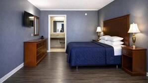 A hotel room with a bed, bedside lamps, a dresser, a TV, and a mirror. - Comfort Room, One king Bed, Non-smoking (Nashville)