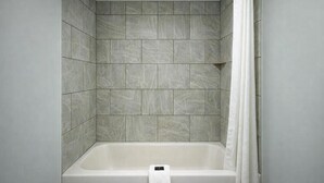 A bathroom with a bathtub, tiled walls, and a white curtain. - Comfort Room, One king Bed, Non-smoking (Nashville)