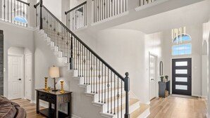 A staircase with black balusters, white walls, and a wooden floor.