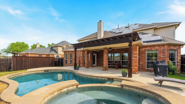 A residential property with a swimming pool, patio, and brick exterior.