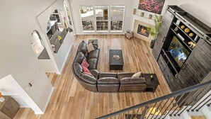 A spacious living area with a sectional sofa, a fireplace, and a staircase.