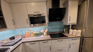 Una cocina moderna con microondas integrado, refrigerador de acero inoxidable y encimera de madera.