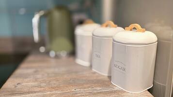 Four white containers with wooden handles on a wooden shelf.