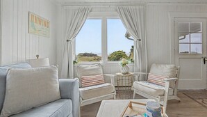 Una habitación con sofá, dos sillones, una mesita y una ventana con cortinas.