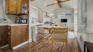 Cucina spaziosa con mobili in legno, zona pranzo con tavolo e sedie in legno e una ventola a soffitto.