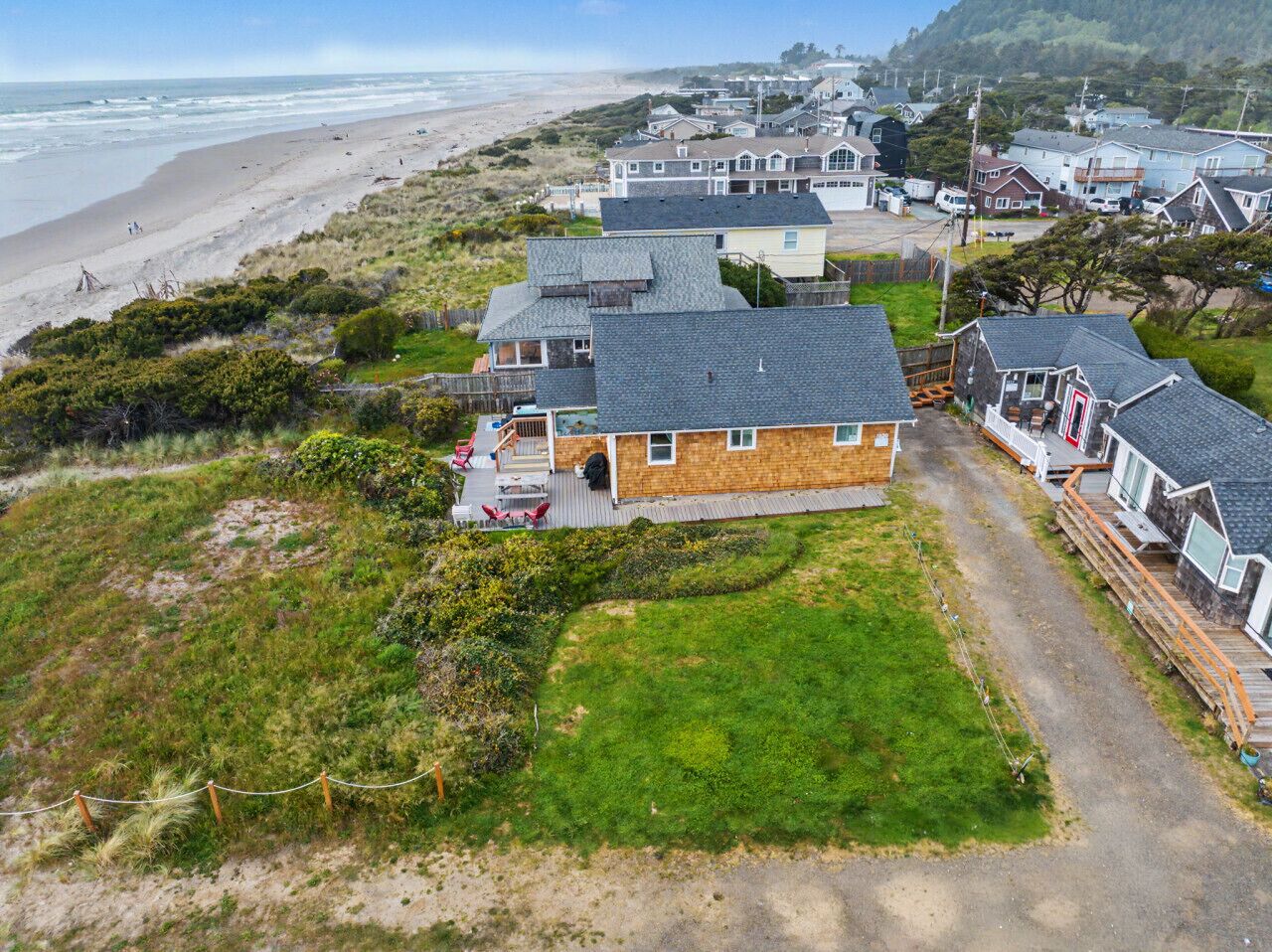 A coastal residential area with houses, a beach, and a grassy field.