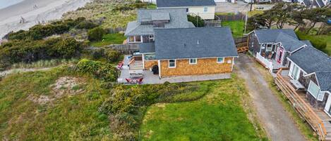 A coastal residential area with houses, a beach, and a grassy field.