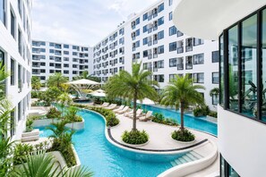 A modern hotel with a central swimming pool surrounded by palm trees and lounge chairs. - Stylish Capri residense BangTao Beach (Choeng Thale)