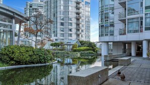 A modern building with a reflective water feature, a small bridge, and a duck on the steps. - Fantastic 1 bed and den in Yaletown across from the world famous Seawall! (Vancouver)