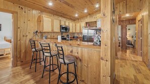 Un interior de madera con cocina, taburetes de bar y una cama.