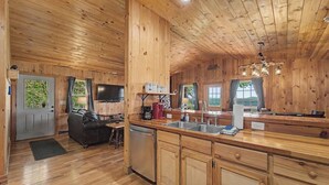 Interior de una cabaña de madera con cocina, comedor y sala de estar.