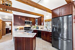Une cuisine moderne avec des meubles en bois, des appareils en acier inoxydable et un grand îlot central.