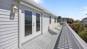 A white building with a covered porch, a lantern, and a window with blinds. - Golden Hour Getaway | Sleeps 12 | Pool + Beach (Atlantic Beach)