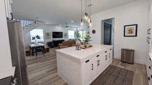 Een moderne keuken met een centraal eiland, een eethoek en een woonkamer met een televisie.