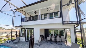 Een twee verdiepingen tellend huis met een overdekt terras, een zwembad en een balkon.