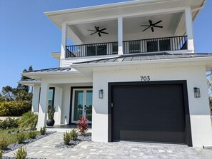 A modern two-story house with a black garage door, a balcony with a railing, and a number '703' on the front wall. - THE TOGETHER PLACE 2 (naples)
