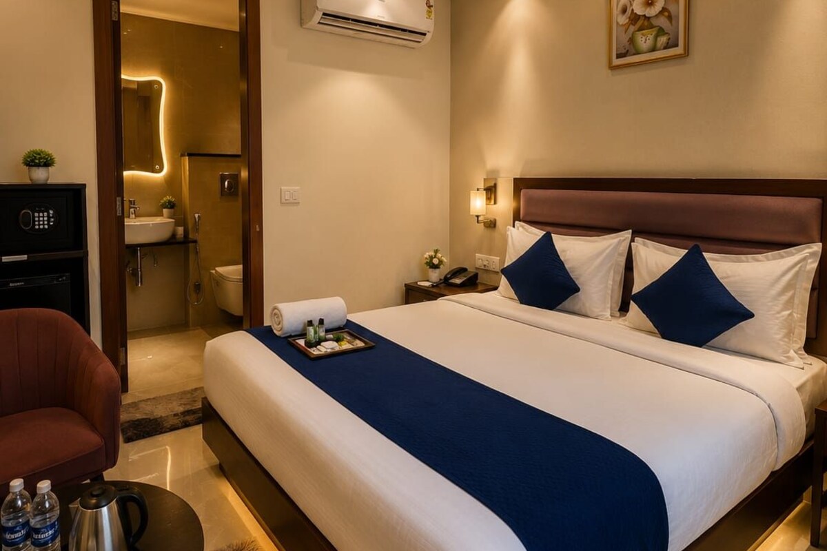 A hotel room with a large bed, bedside table, and a desk with a chair.