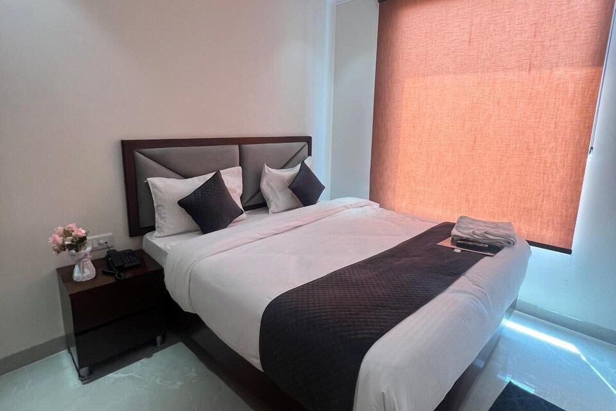 A bedroom with a bed, a nightstand, a ceiling fan, a window with blinds, and a small rug.