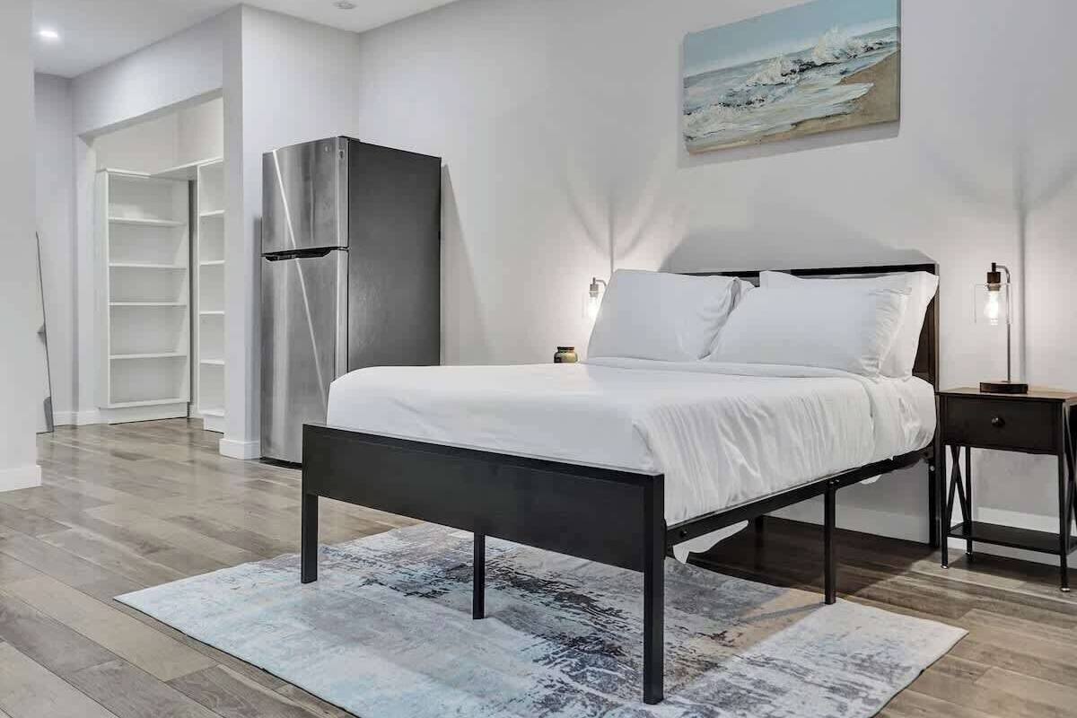 A modern bedroom with a bed, a wardrobe, a nightstand, and a painting on the wall.