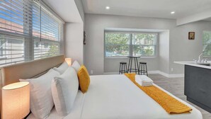A modern hotel room with a large bed, a small dining area, and a view of the outdoors. - 906 North Riverside Dr (Pompano Beach)