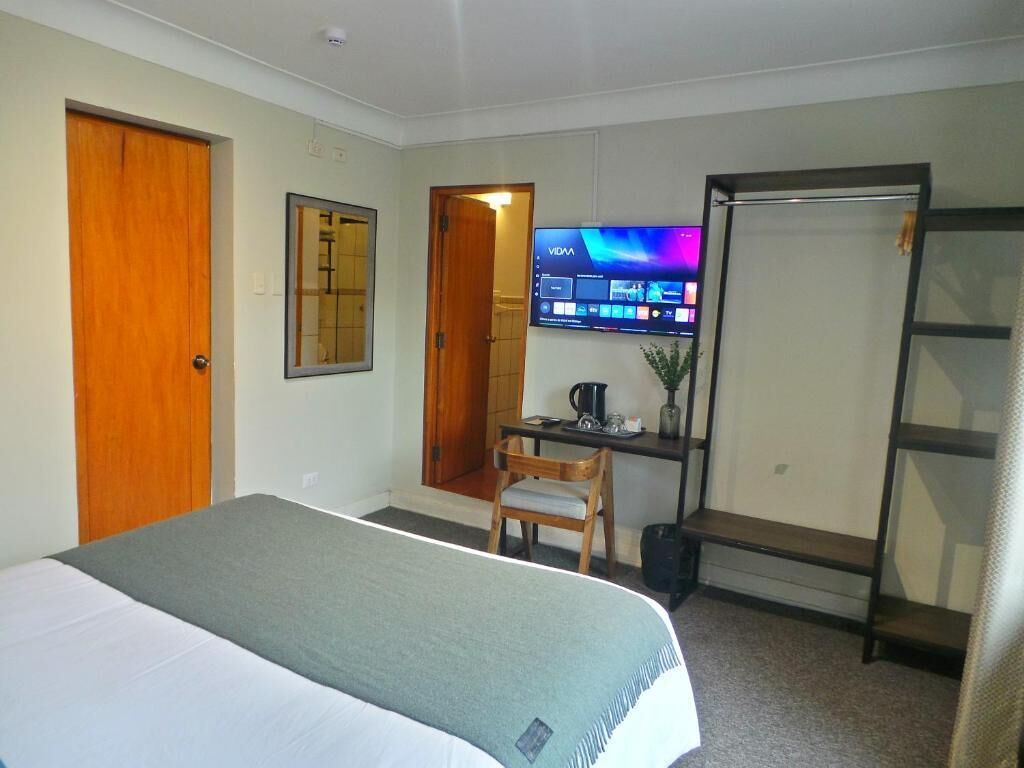 Une chambre d’hôtel comprenant un lit, un bureau avec une chaise, une télévision et une armoire.