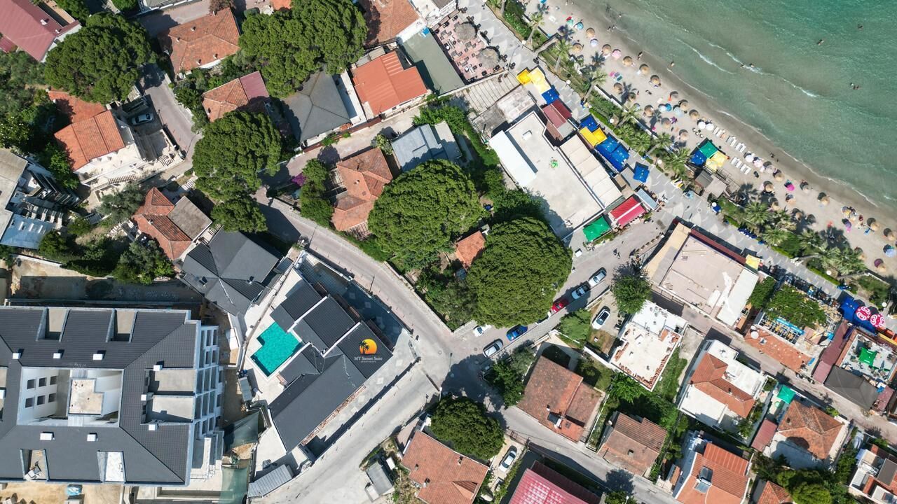 An aerial view of a coastal town with buildings, a beach, and a road.