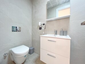 A bathroom with a toilet, a sink, and a mirror. - My Sunset Suite Apartments (Kuşadası)