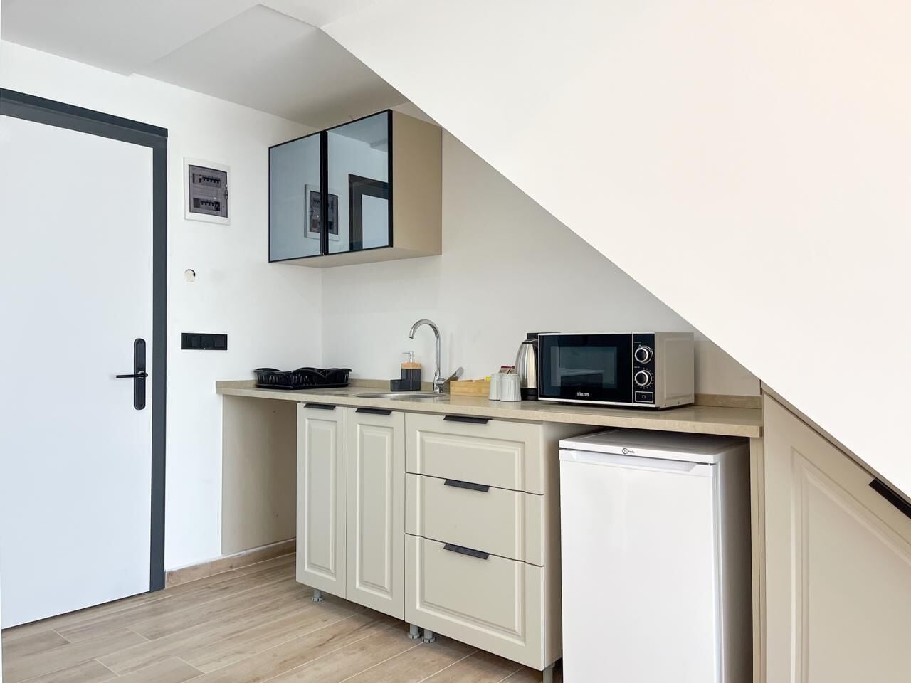 A compact kitchen with a microwave, sink, and cabinets.