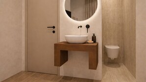 A bathroom with a wooden vanity, a round mirror, a white sink, and a toilet. - CAVO III Luxury Rooms (Chania)