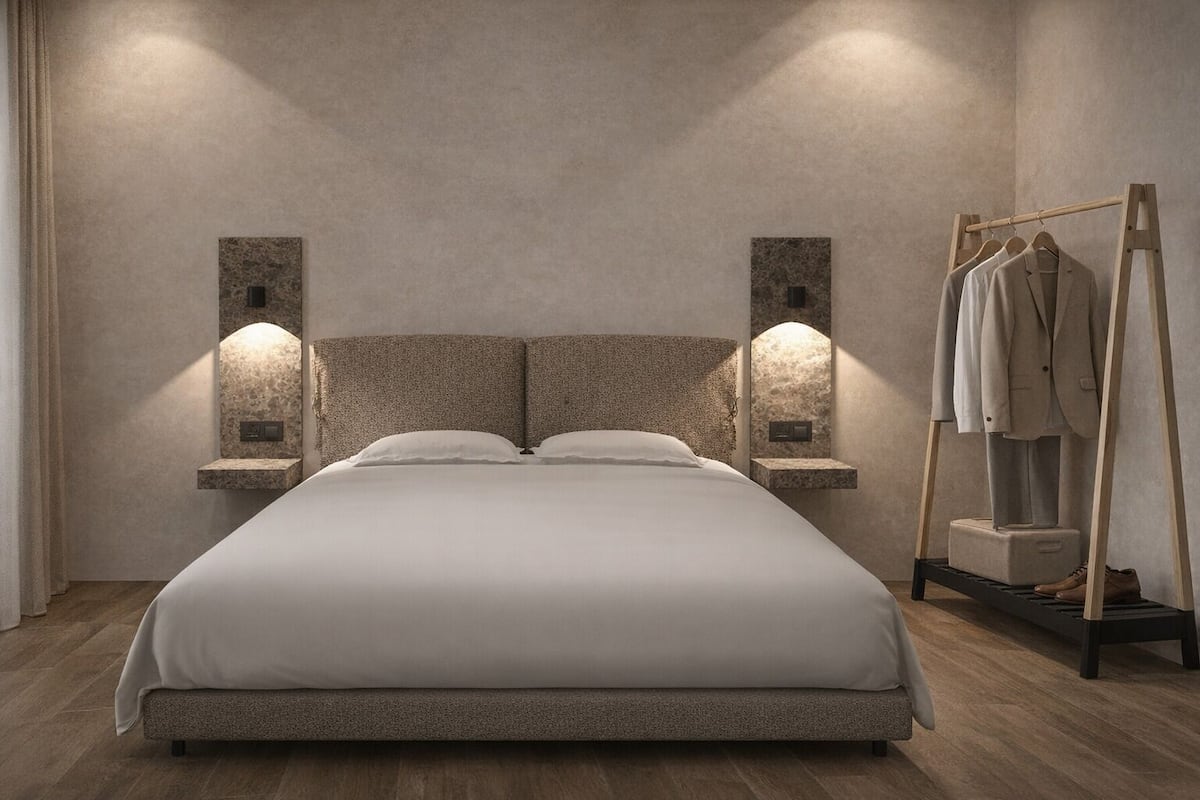 A bed with a headboard, two wall-mounted lights, a wooden floor, and a clothing rack with a mannequin.