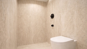 A bathroom with a toilet, a shower area, and a wall-mounted faucet. - CAVO III Luxury Rooms (Chania)